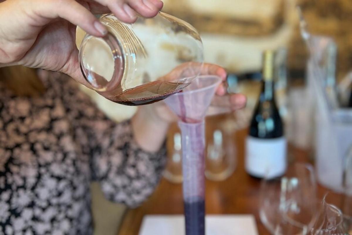 a person pouring a drink into a wine glass