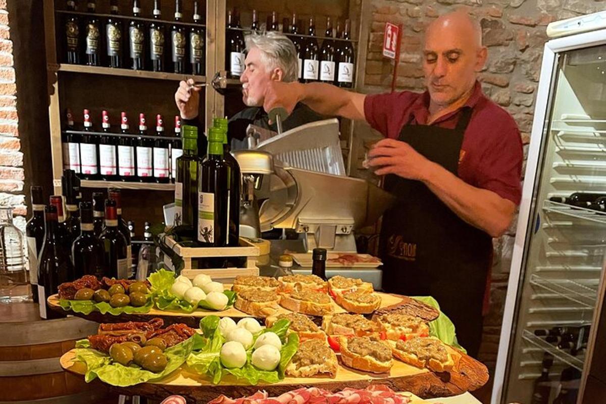 two men standing behind a counter with bottles of wine