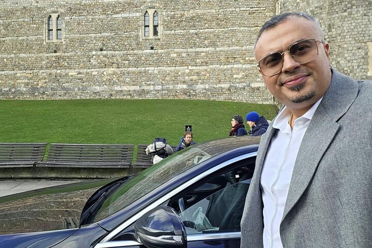 un uomo in giacca e cravatta in piedi accanto a un'auto