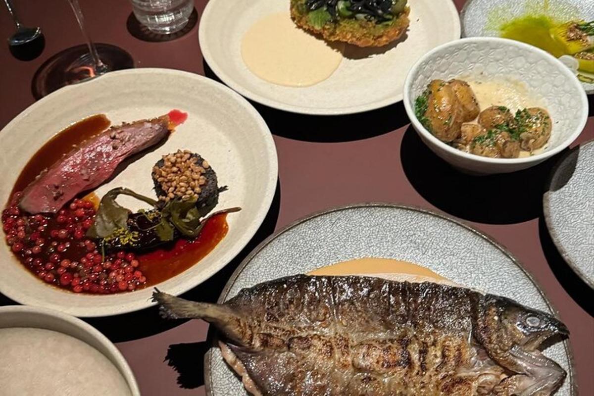 Una mesa con platos de comida y un pescado encima.