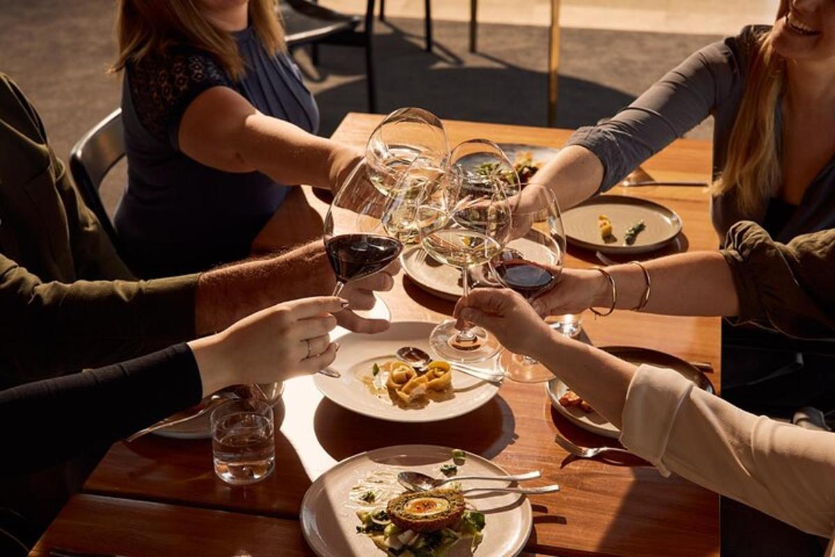 un grup de oameni așezați în jurul unei mese cu pahare de vin