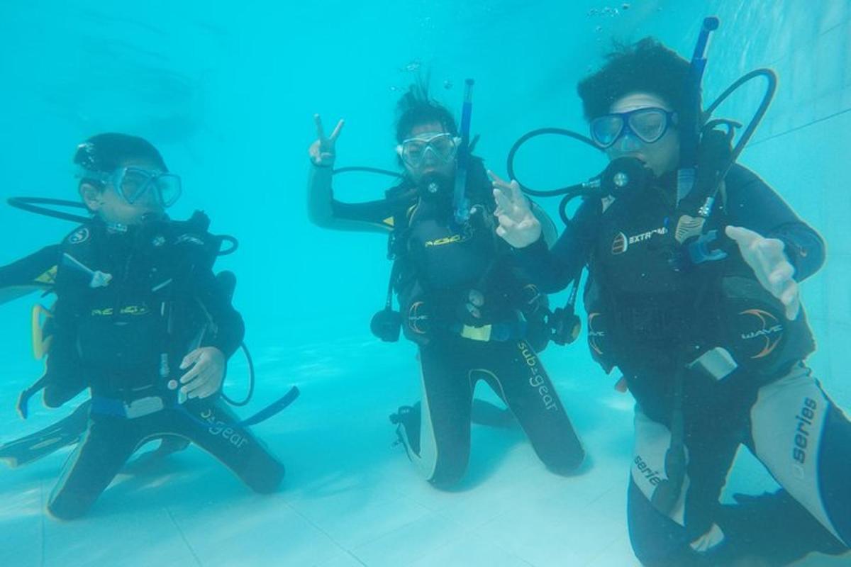 sekelompok tiga orang di dalam air dengan peralatan selam