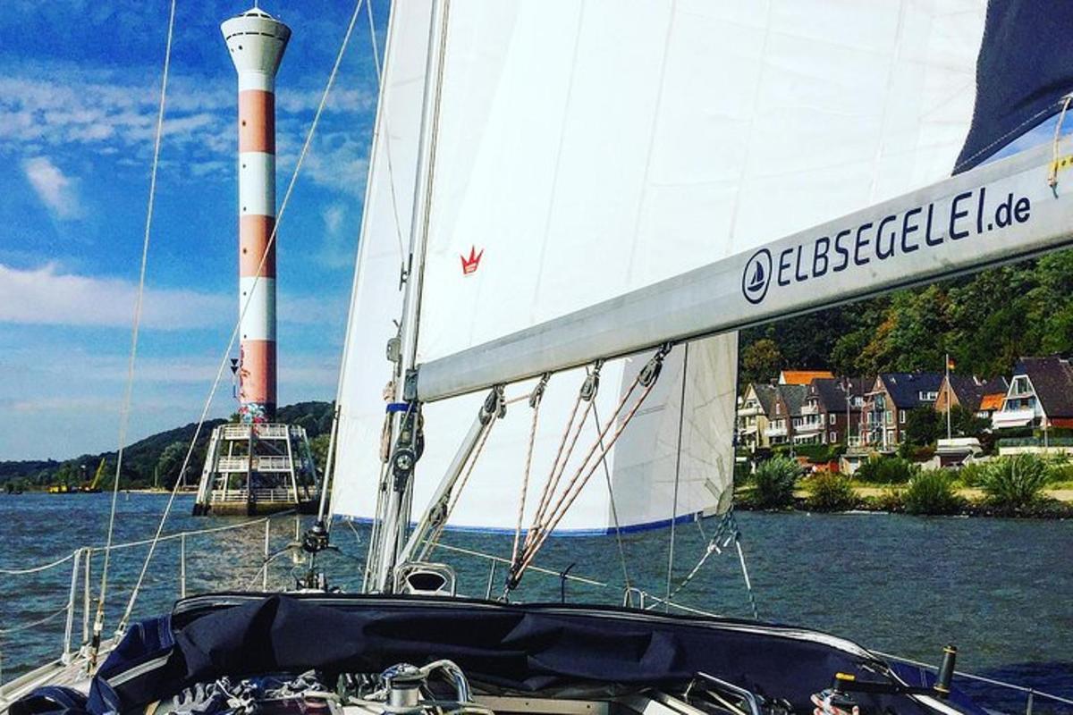 egy vitorlás a vízben, a háttérben egy világítótorony