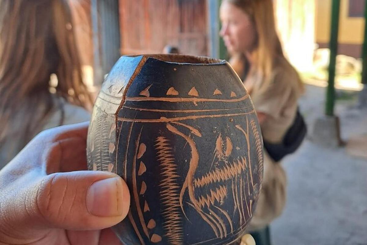 a hand holding a vase with a person in the background
