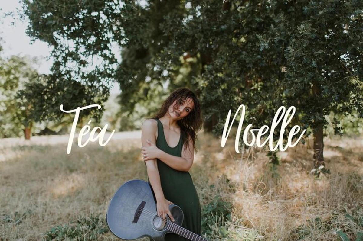 a woman in a green dress holding a guitar