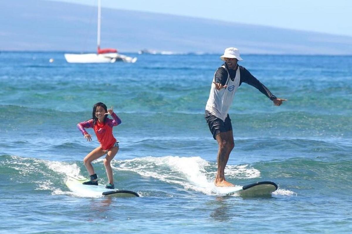 un home i una nena petita sobre taules de surf a l'oceà