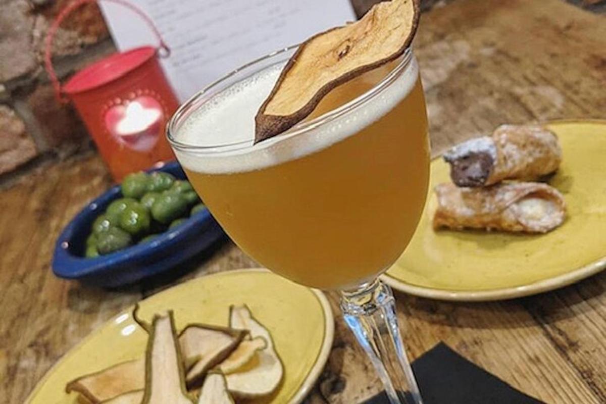 Un vaso de cerveza en una mesa con un plato de comida.