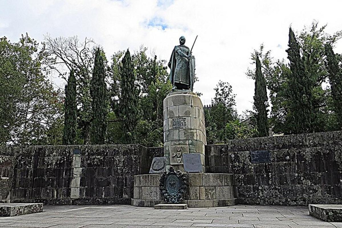 uma estátua de um homem em pé no topo de um muro de pedra