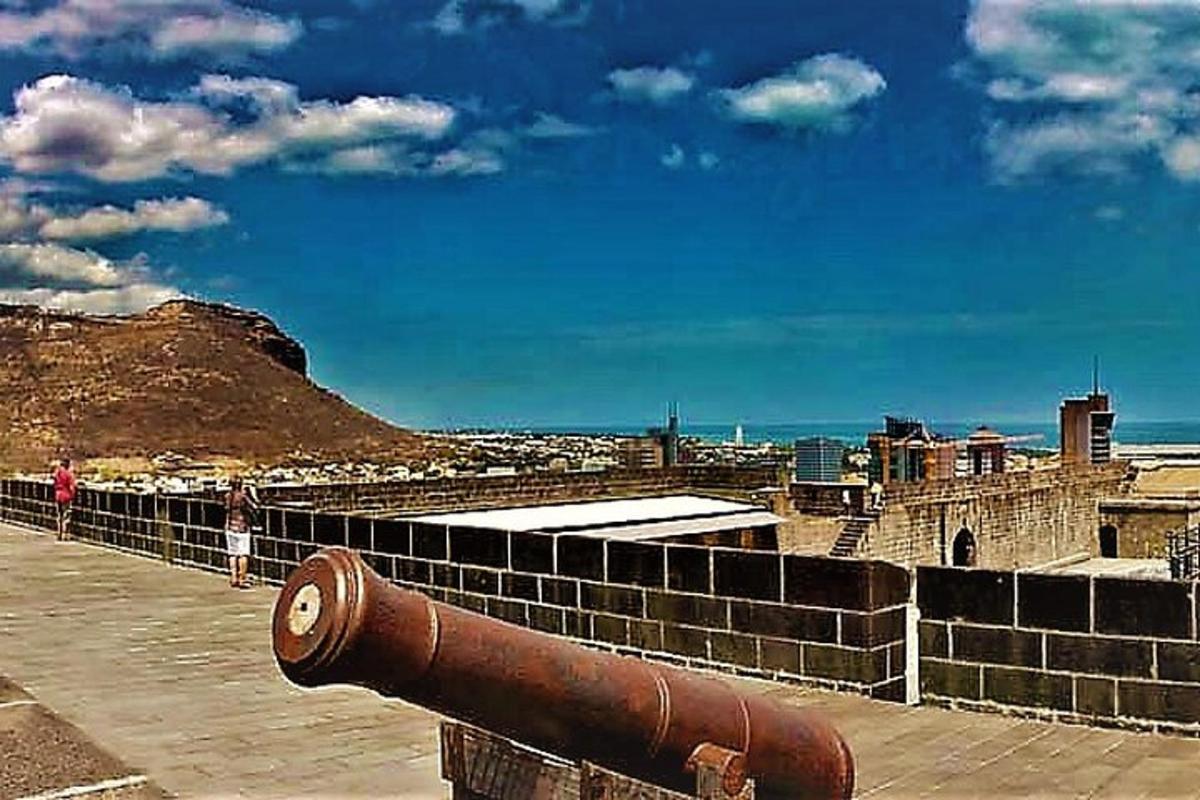 a cannon on the side of a wall near the ocean
