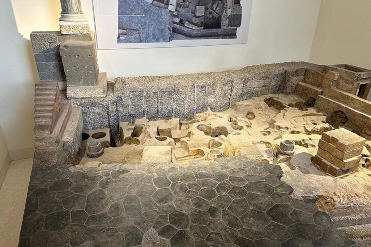 Una habitación con piso, reconstrucción de un edificio con rocas y artefactos.
