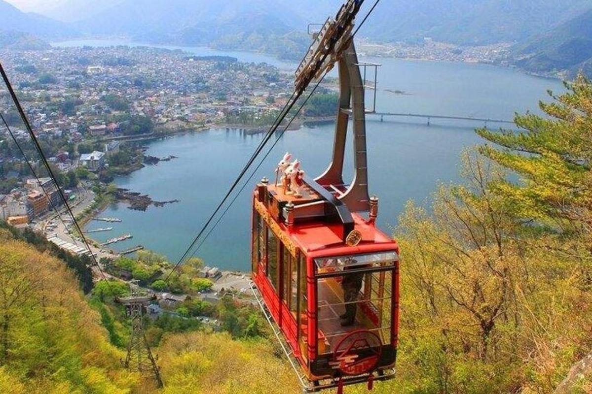 červená lanovka stoupající na kopec poblíž řeky