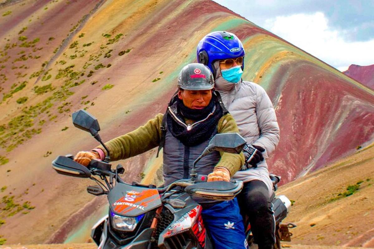 Dos personas en una motocicleta frente a una colina