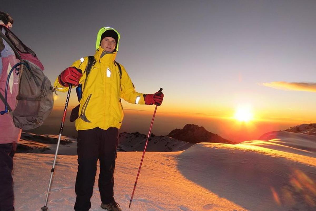 un uomo in piedi sulla cima di una montagna coperta di neve