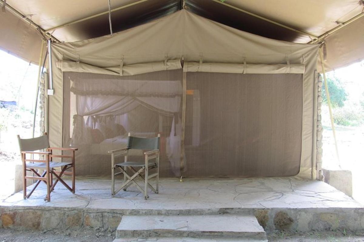 uma tenda com duas cadeiras e uma mesa embaixo dela