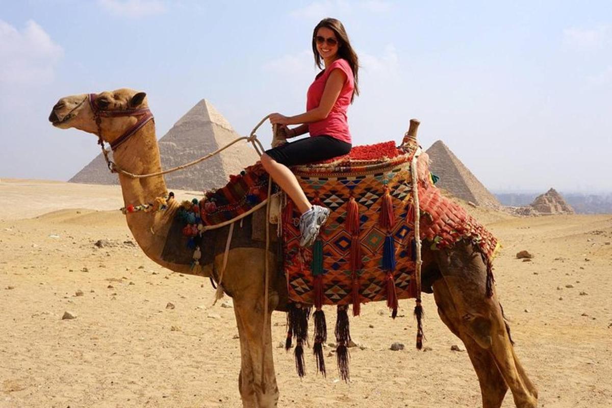 žena jedoucí na hřbetě velblouda v pyramidách