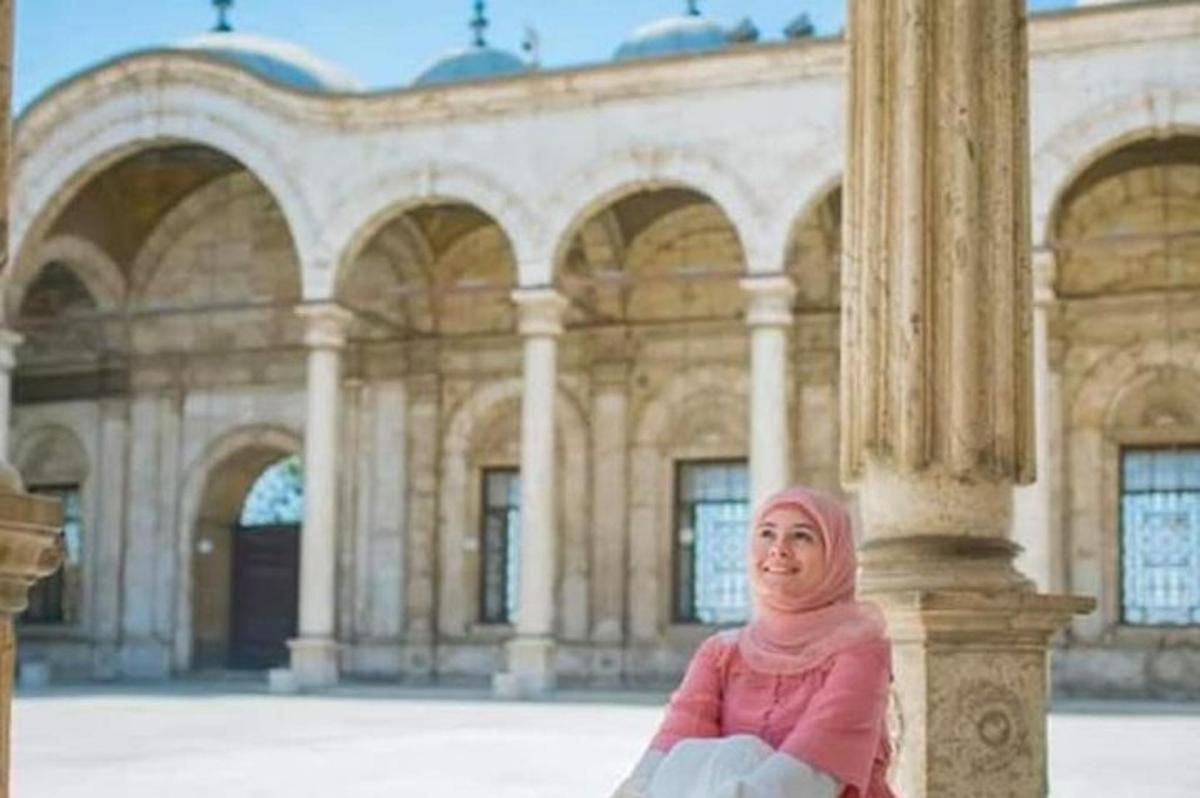 žena sedící na sloupu před budovou
