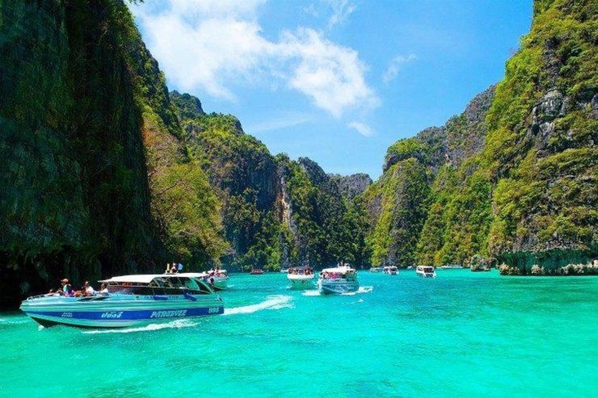 Un grupo de barcos en el agua cerca de una montaña.