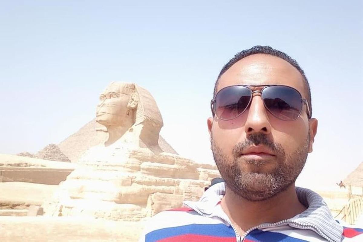 un uomo con occhiali da sole in piedi davanti alla sfinge