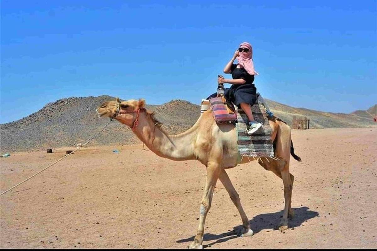 una donna a cavallo di un cammello nel deserto