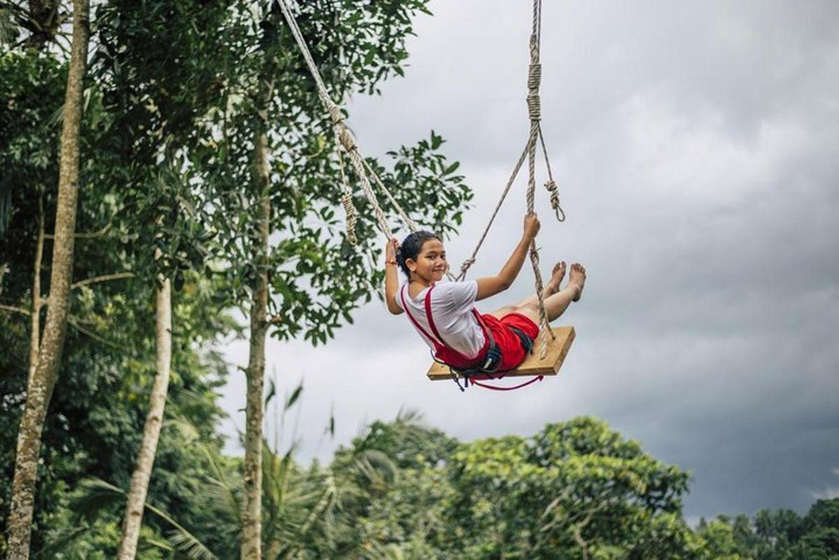 a woman swinging on a rope swing in the jungle