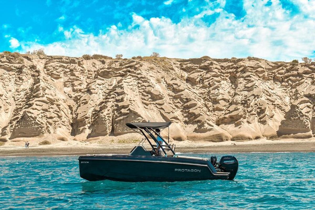 a black boat in the water next to a mountain