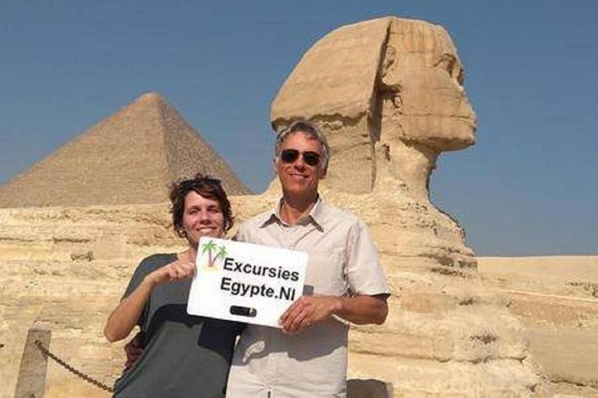 muž a žena držící ceduli před pyramidami