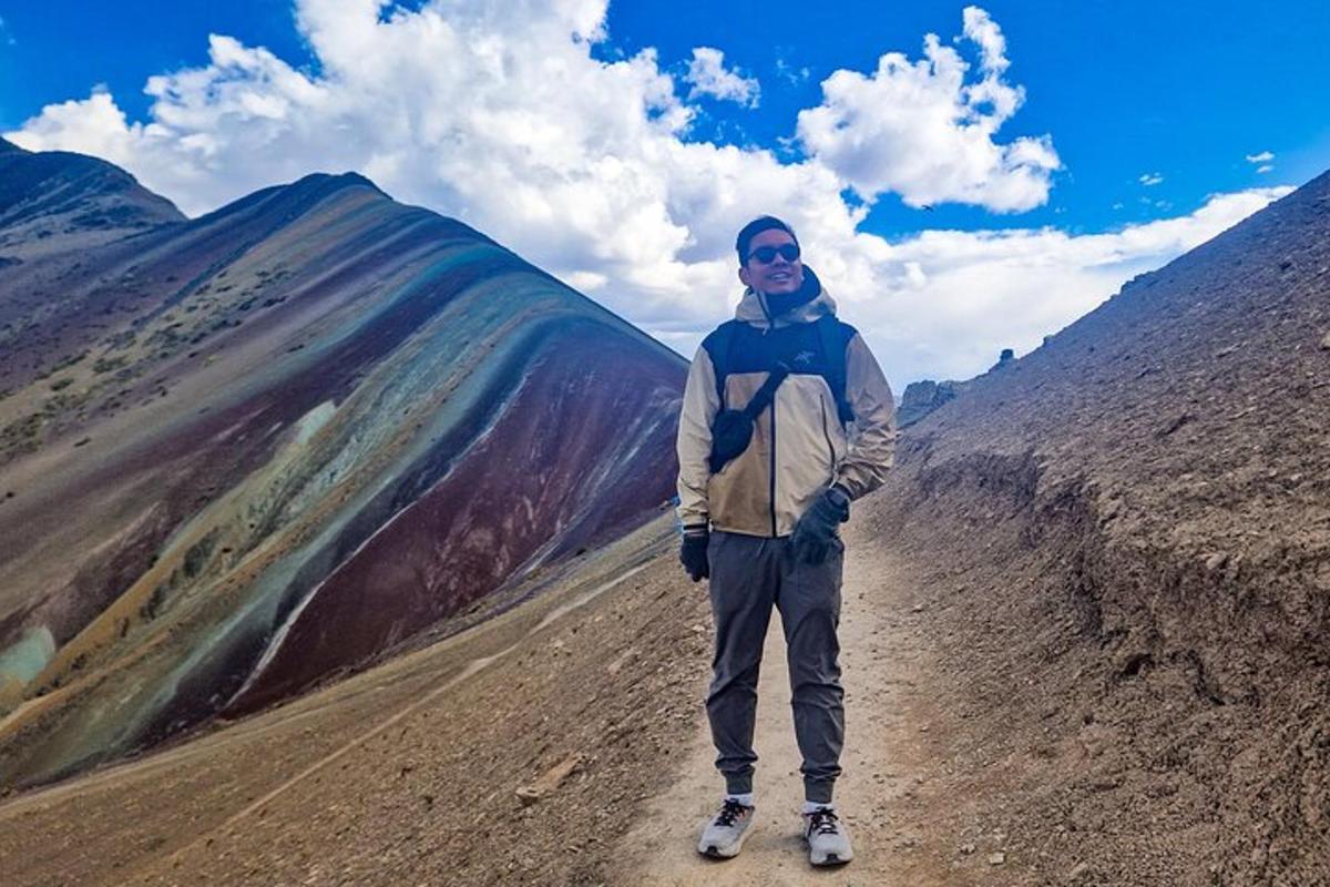 Un hombre parado en un camino de tierra en una montaña.