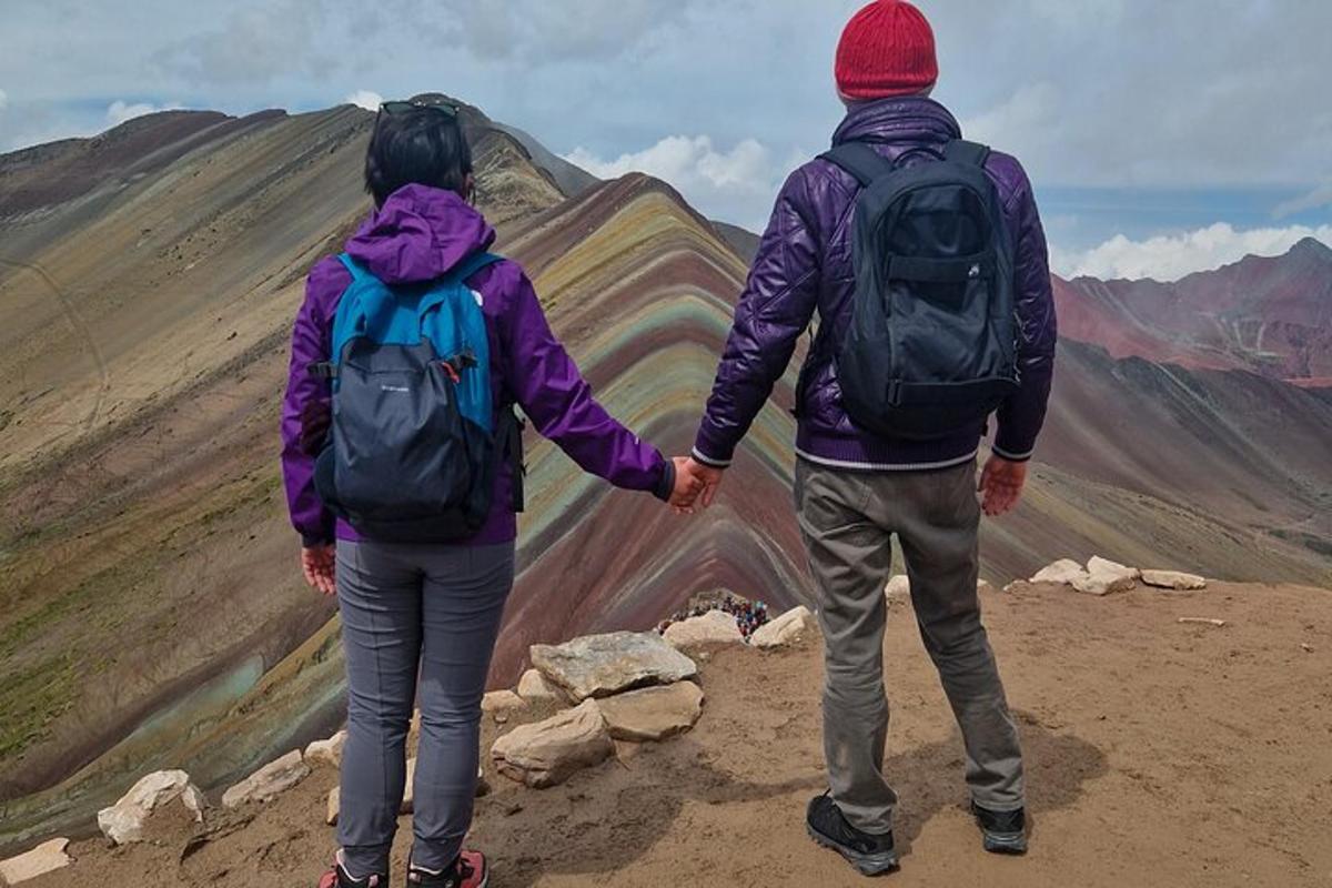 Tveir menn haldast í hendur á fjallstindi