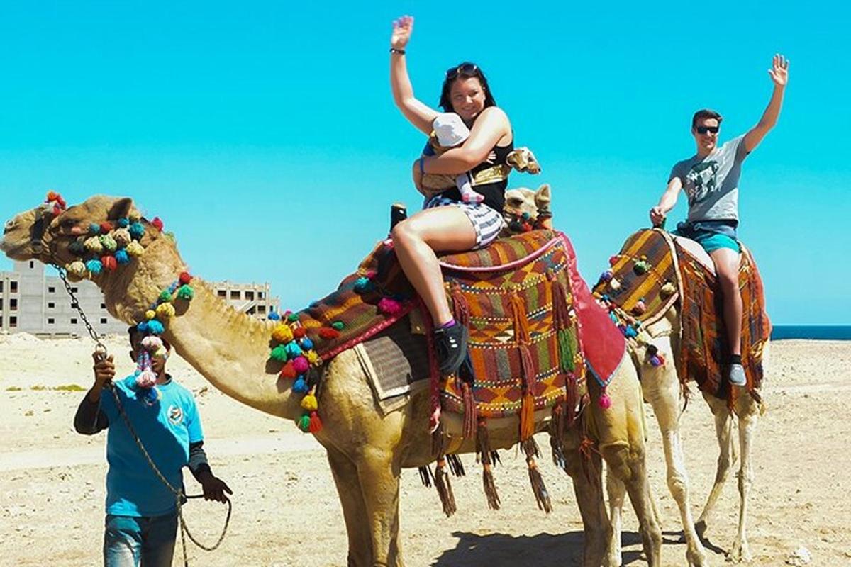 a woman riding on the back of a camel on the beach