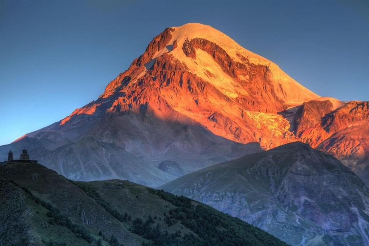 pemandangan gunung dengan matahari bersinar di atasnya