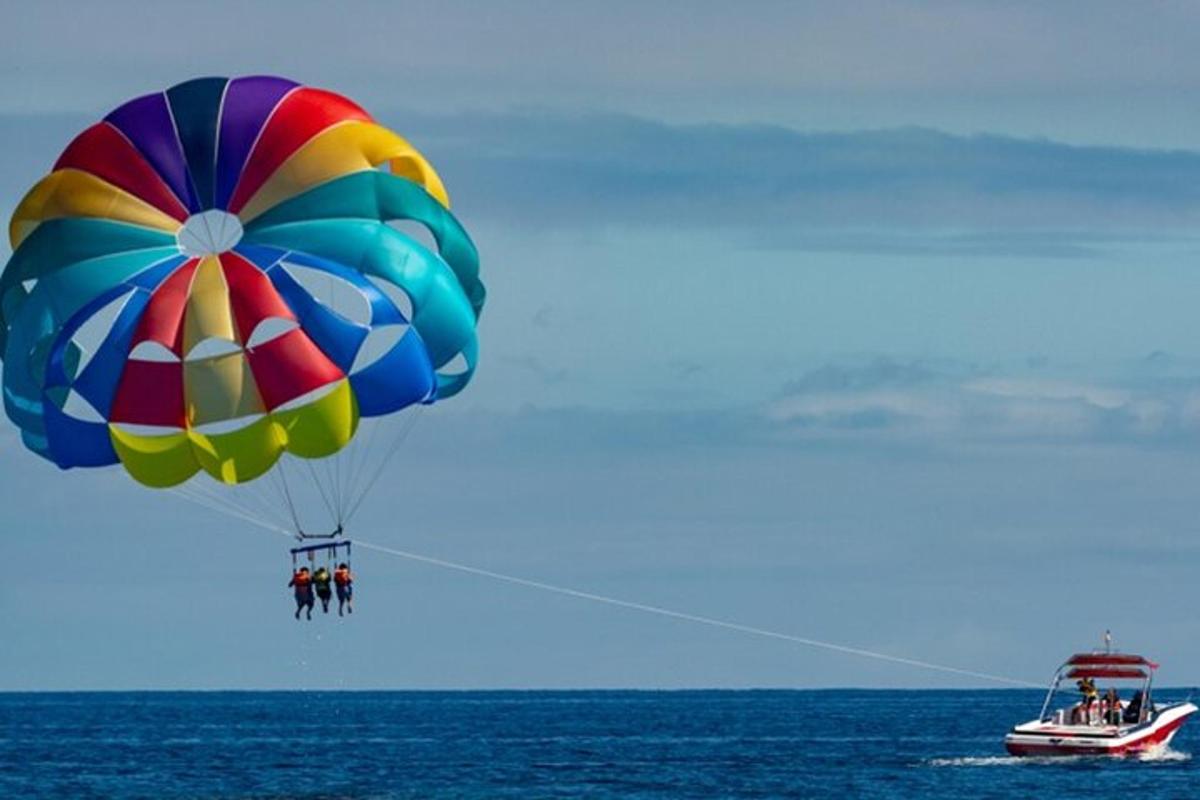 Un paracaídas colorido volando sobre el océano con un barco.
