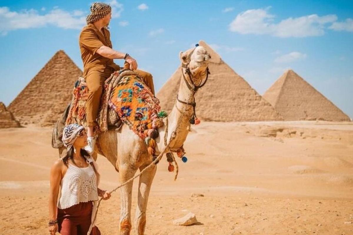 en mann som rir på en kamel foran pyramidene