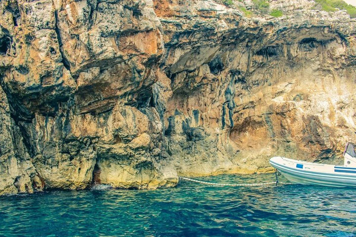 una barca a l'aigua al costat d'un penya-segat rocós