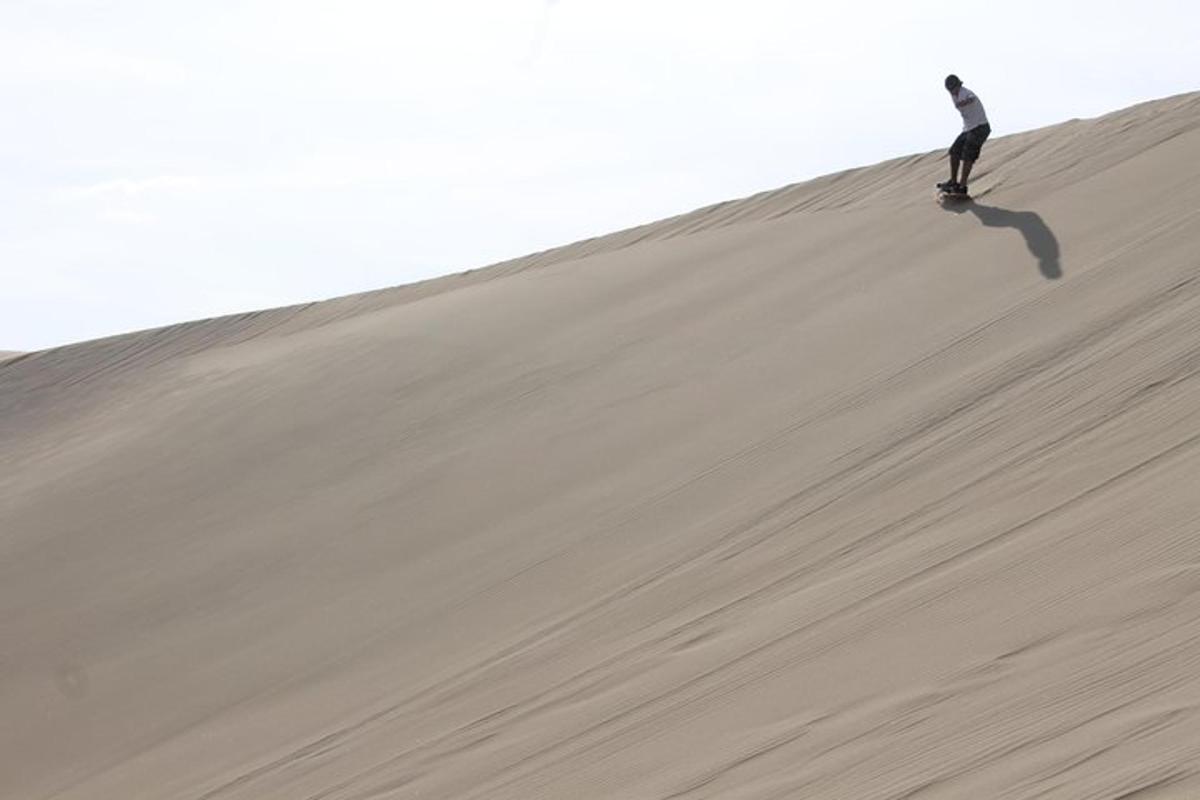 een man die op een skateboard op een zandduin rijdt