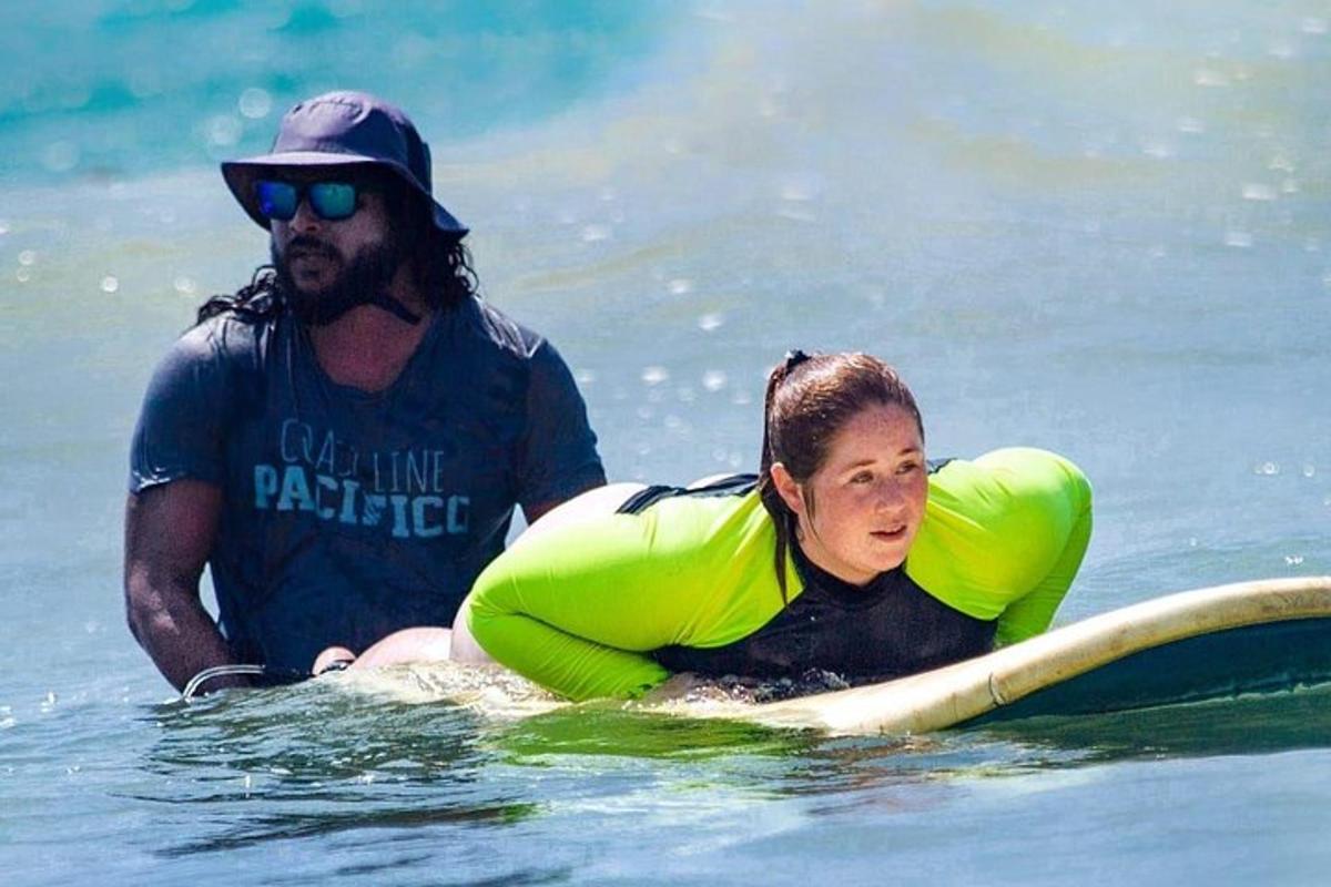 en mann og en kvinne på et surfebrett i vannet