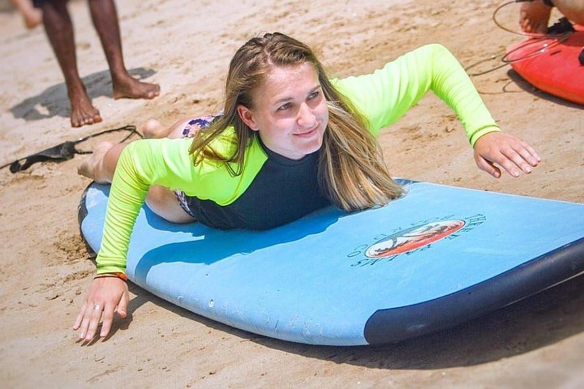 a young girl laying on a surfboard on the beach