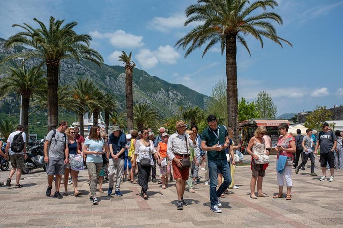 a group of people walking down a street with palm trees