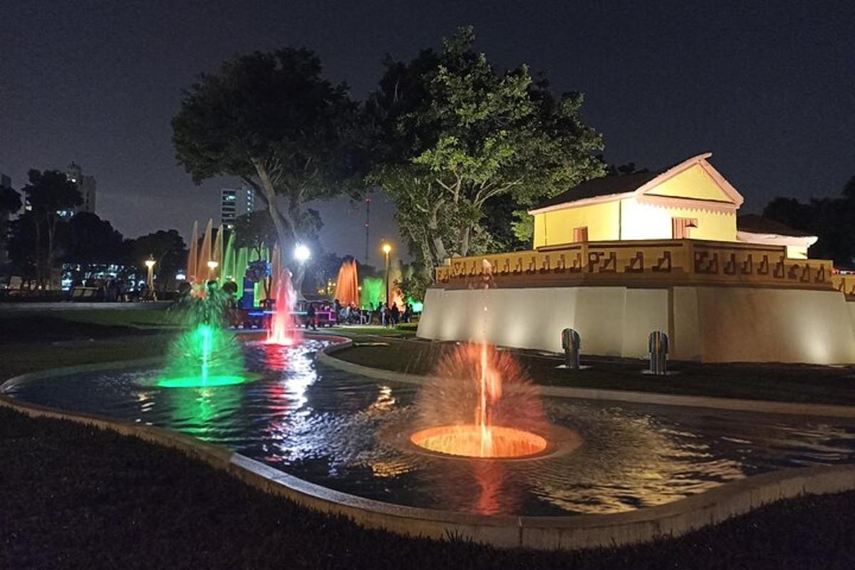 a fountain in front of a building at night