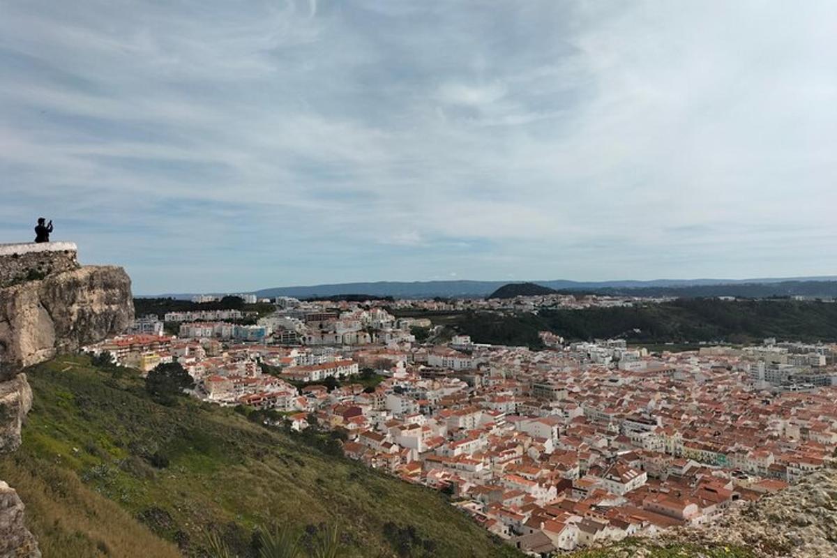 osoba sedící na vrcholu kopce s výhledem na město
