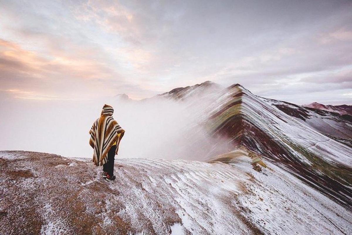 una persona in piedi sulla cima di una montagna coperta di neve
