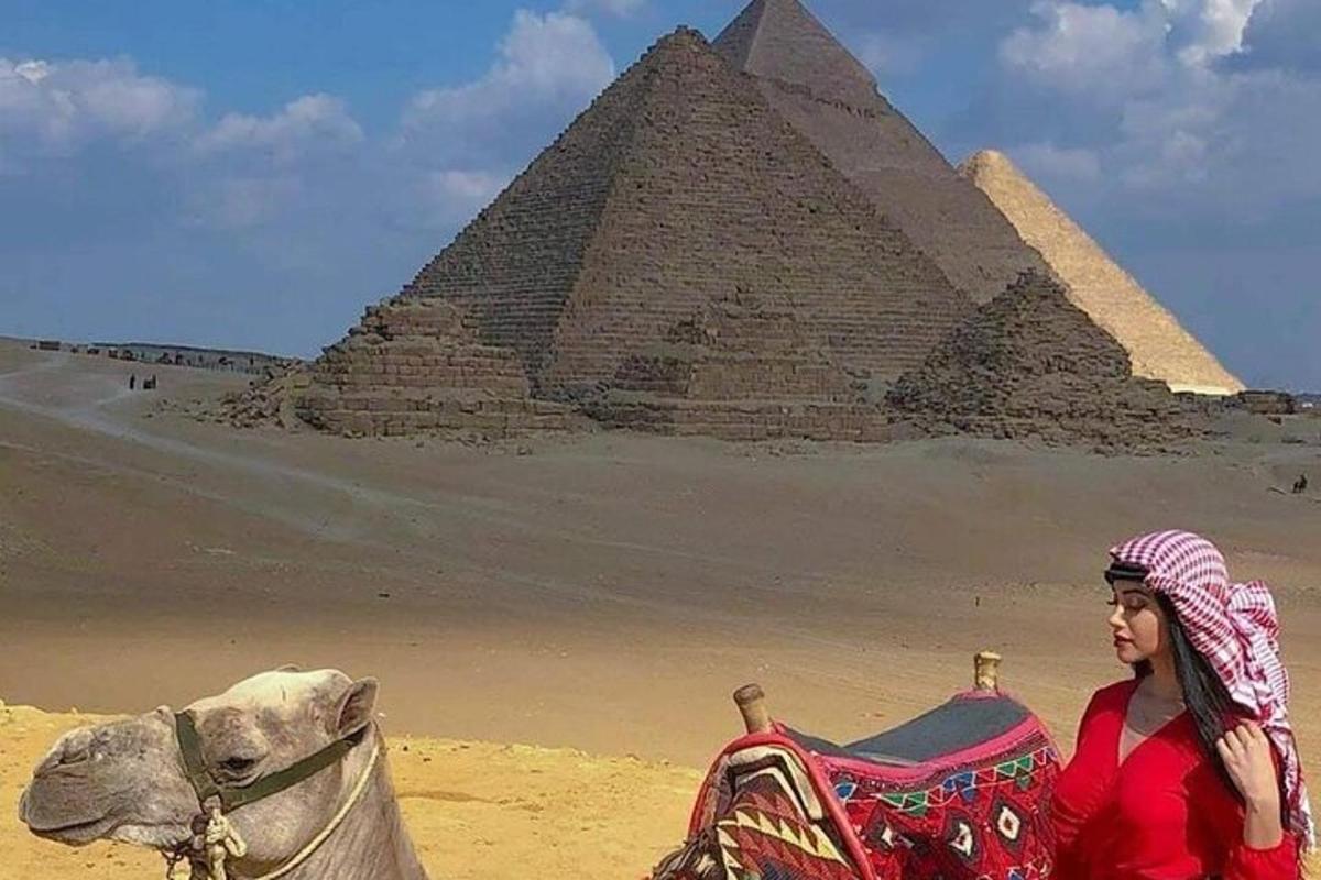 žena jazdiaca na ťave pred pyramídami