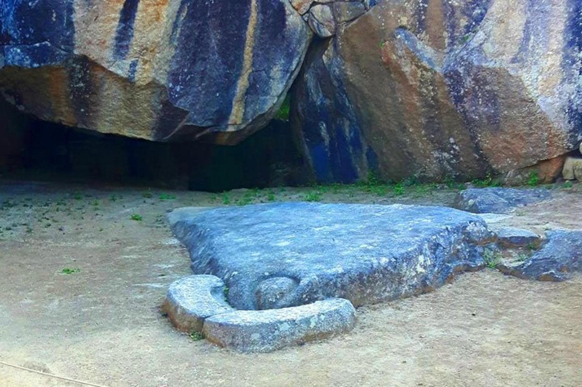 um banco de pedra sentado ao lado de uma grande rocha