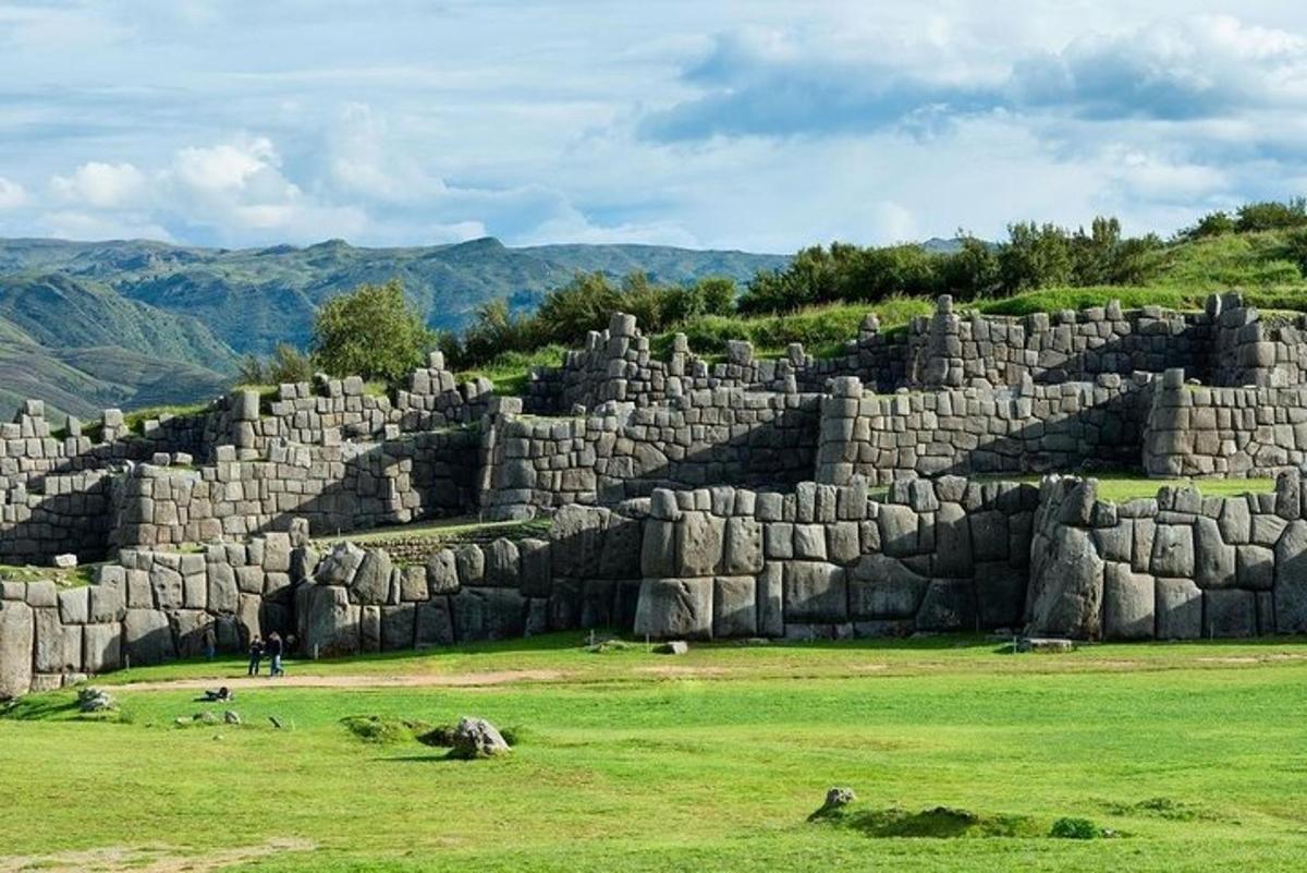 un grande muro di pietra in un campo con le montagne sullo sfondo