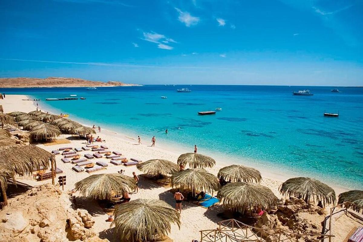 plaža s slamnatimi senčniki in ljudmi na plaži