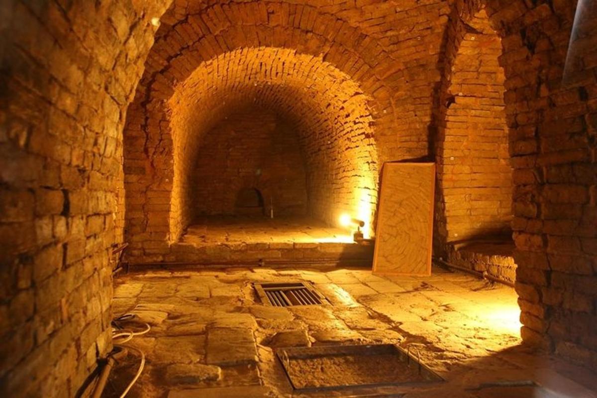 un vecchio tunnel di mattoni con una grata nel pavimento