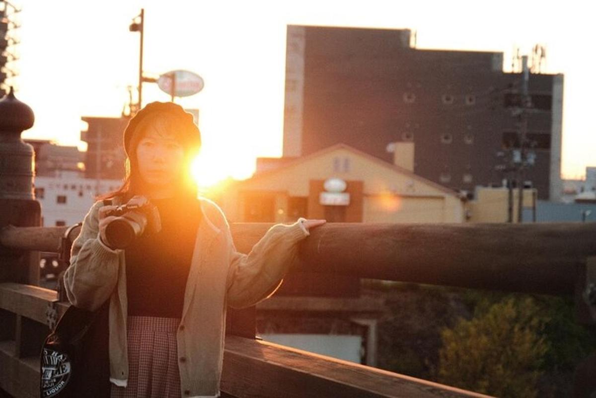 a woman standing on a balcony with the sun setting