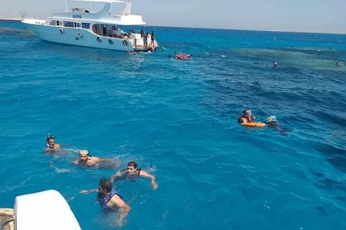 a group of people swimming in the water with a boat