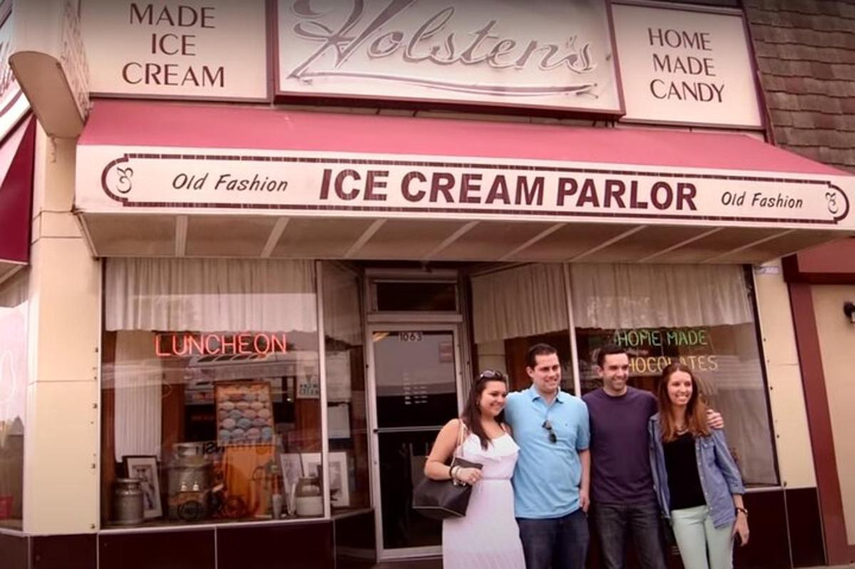 a group of people standing in front of a ice cream parlor
