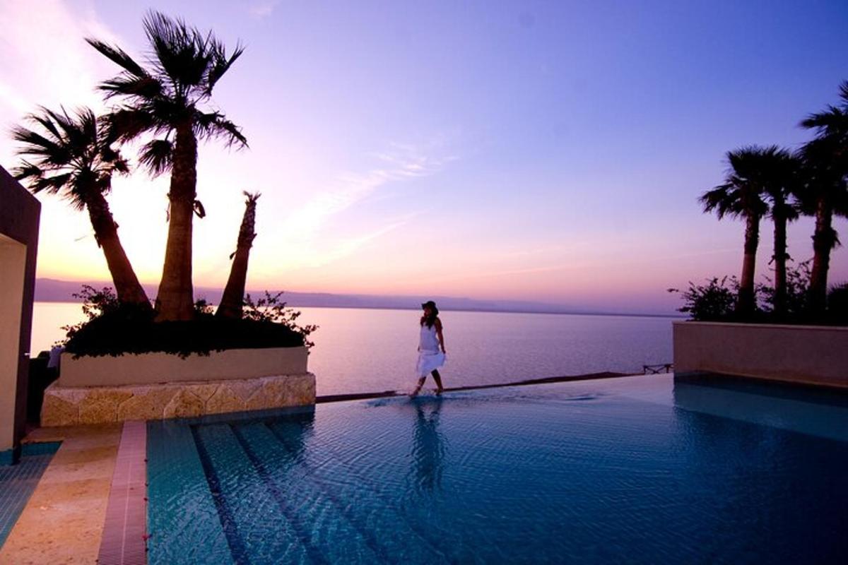 a woman walking around a pool with a view of the ocean