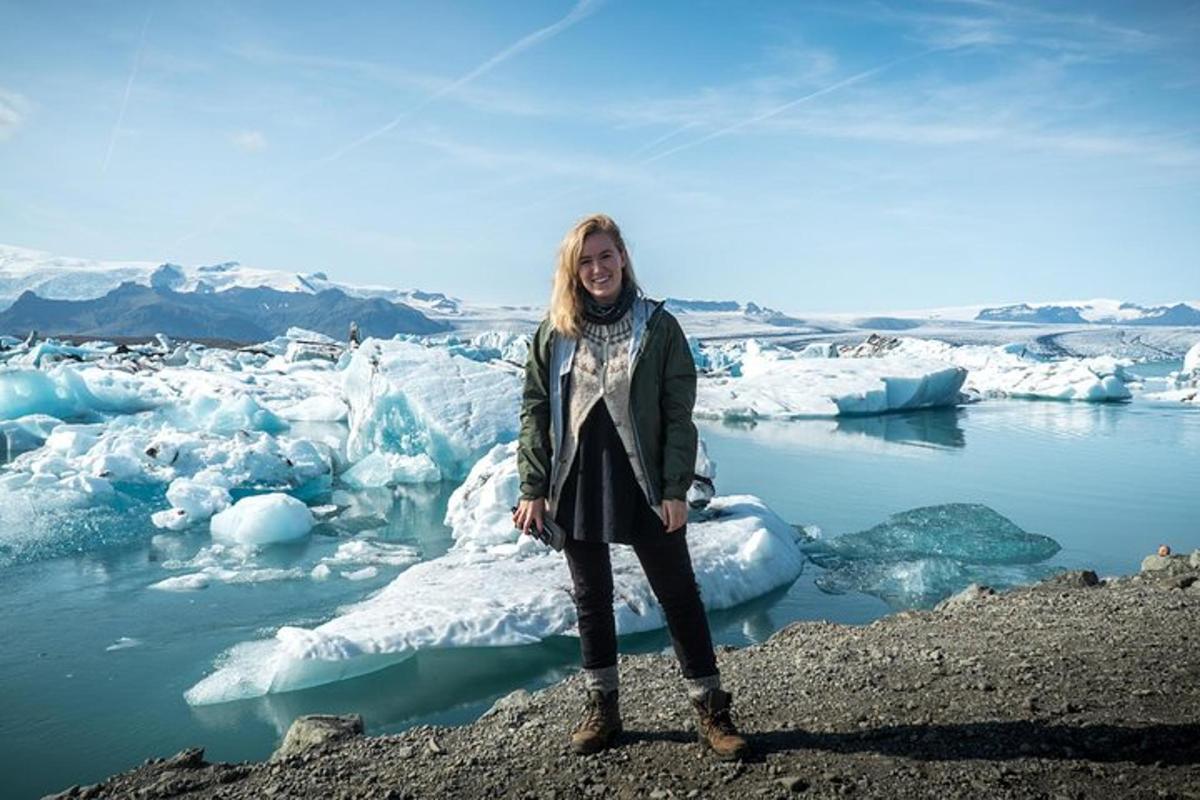 uma mulher parada em frente a icebergs na água